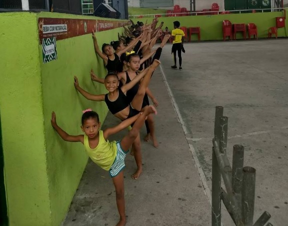 Meninas fazem exercício apoiadas na parede.